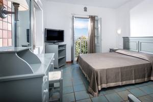Ein Schlafzimmer im Silva Beach Hotel mit Fernseher, Bett, Nachttischen und einem Balkon.