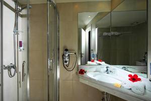 Badezimmer im Silva Beach Hotel mit Glasdusche, Handtuchtrockner und Spiegel.