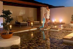 Außenpool des Lindos Bay Hotels bei Nacht mit Lounge-Stühlen, Kerzen und Gehweg aus Kieselsteinen