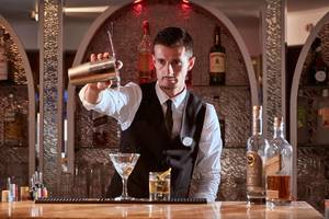 Ein Barkeeper im Grecian Park Hotel gießt einen Cocktail in ein Glas.