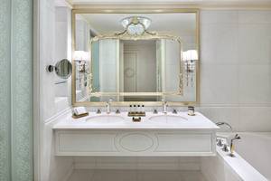 Badezimmer im Raffles The Palm Dubai mit einem großen Spiegel und zwei Waschbecken.