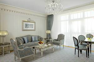 Wohnzimmer im Raffles The Palm Dubai Hotel mit Kristallkronleuchter, Sofa und Esstisch.