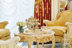 Wohnzimmer im Raffles The Palm Dubai mit einem Tee-Karussell und goldenen Möbeln.