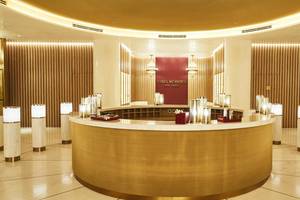 Empfangsbereich des Cing Mondes Spa im Raffles The Palm Dubai mit goldenem Tresen und weißen Säulen.