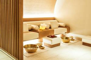 Spa-Behandlungsraum im Raffles The Palm Dubai mit weißen Möbeln, Holzelementen und Kerzen.