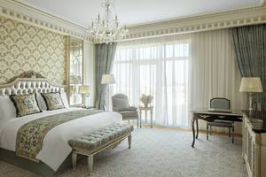 Schlafzimmer im Raffles The Palm Dubai mit großem Bett, Kristallkronleuchter, und Schreibtisch