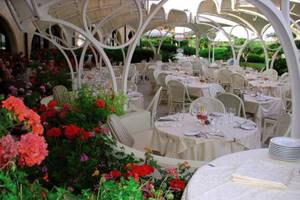 Außenbereich des Baia Di Nora Restaurants mit gedeckten Tischen und farbenfrohen Blumen.