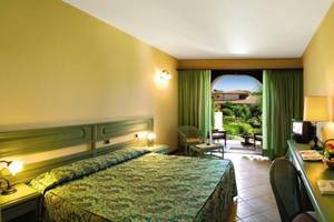 Hotelzimmer im Baia Di Nora mit Bett, Schreibtisch und Gartenblick