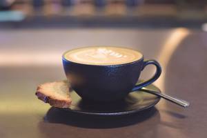 Eine Tasse Kaffee mit Gebäck auf einem dunklen Untergrund.