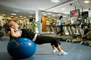 Frau im Fitnessstudio mit einem blauen Trainingsball im Swissotel Al Murooj Dubai