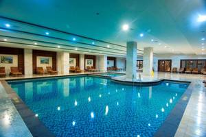 Innenpool des Orange County Belek - Family Concept Hotels mit blauen Fliesen und Lounge-Stühlen.