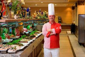 Ein Koch im Orange County Belek - Family Concept Hotel steht vor einem Buffet.