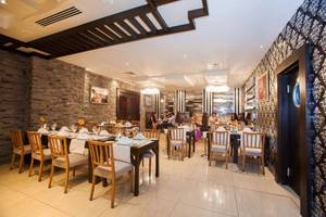 Innenansicht des Restaurants im Orange County Belek Hotel mit gedeckten Tischen und dekorierten Wänden.