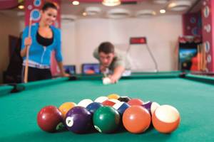 Mann spielt Billard im Hotel Orange County Belek, Frau schaut zu.