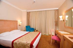 Hotelzimmer im Orange County Belek Family Concept mit Doppelbett, blauem Stuhl und Schreibtisch.