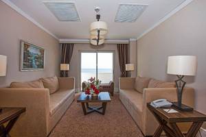 Hotelzimmer mit Meerblick, zwei Sofas, Tisch, Blumen, Telefon und Lampen.