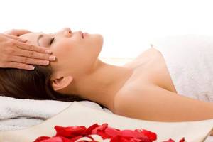 Frau genießt eine Kopfmassage im Hotel Barcelo Tenerife mit roten Rosenblättern.