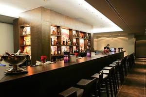 Bar im Barcelo Tenerife Hotel mit Tresen, Flaschen und Stühlen.