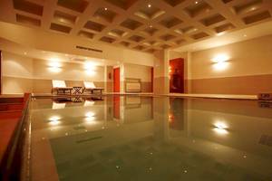 Innenpool des Aegean Pearl Hotels mit Lounge-Sesseln und beleuchteten Wänden.