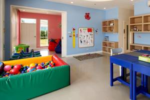 Kinderzimmer im Kantary Beach Hotel mit blauen Wänden, bunten Spielsachen und Regalen.