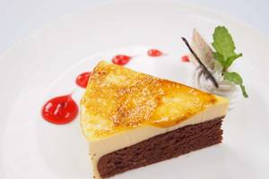 Schnitt eines Schokoladenkuchens mit Creme und Beeren auf einem weißen Teller