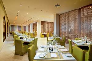 Innenbereich des Restaurants im Juweira Boutique Hotel mit grünen Stühlen und Tischen.
