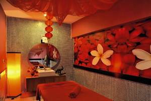 Spa-Behandlungsraum im Seaden Corolla Hotel mit rotem Dekor, großen Blumentapeten und Entspannungsmöbeln.