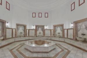 Innenbereich der Sauna im Kremlin Palace Hotel mit weißen Marmorwänden und acht Waschbecken.