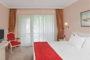 Innenansicht eines Hotelzimmers im Kremlin Palace Hotel mit Fernseher, Bett und Stuhl.