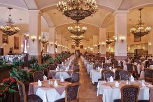 Restaurant im Kremlin Palace Hotel mit gedeckten Tischen und Kronleuchtern.
