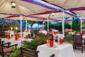 Überdachtes Restaurant des Kremlin Palace Hotels mit gedeckten Tischen und roten Tischtüchern.