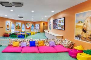 Kinderzimmer im Kremlin Palace Hotel mit bunten Möbeln, Kissen und Gemälden an der Wand.