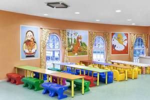 Ein Kinderzimmer im Kremlin Palace Hotel mit bunten Tischen und Stühlen, Wandgemälden und hellem Boden.