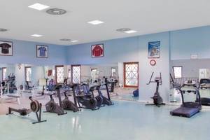 Fitness-Center im Kremlin Palace Hotel mit verschiedenen Trainingsgeräten und Spiegeln.