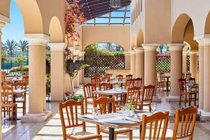 Restaurantbereich des Jaz Mirabel Beach Hotels mit freien Tischen und Stühlen unter einem Dach.