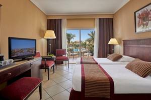 Doppelzimmer im Jaz Mirabel Beach Hotel mit zwei Betten und Fernseher.