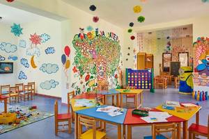 Kinderzimmer im Jaz Mirabel Beach Hotel mit bunten Wandgemälden, Tischen und Stühlen für Aktivitäten.