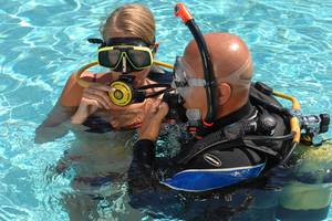 Eine Frau und ein Mann tauchen im Schwimmbecken des Marti Resorts, beide tragen Tauchausrüstung.