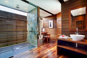 Innenansicht des Badezimmers im Gangehi Island Resort mit Glasdusche, Holzwänden und Möbeln.