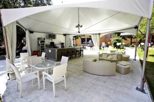 Terrasse des Gladiola Star Hotels mit weißen Möbeln, Bar und Schirm.