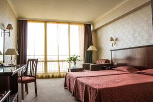 Doppelzimmer im Gladiola Star Hotel mit zwei Betten, Schreibtisch und Fenstern.