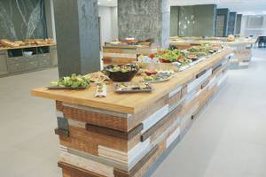 Buffettisch im Gladiola Star Hotel mit verschiedenen Gerichten auf Holzplatte.