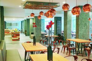 Innenbereich des Gladiola Star Hotels mit runden Kupferlampen und grünen Säulen.