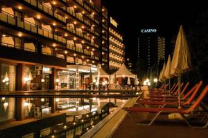 Poolbereich des Gladiola Star Hotels bei Nacht mit beleuchteten Liegestühlen und Gebäuden.