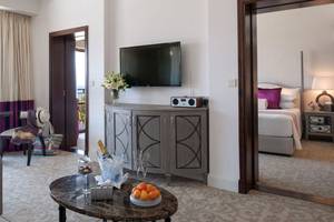 Innenansicht der Suite im Elysium Hotel mit Fernseher, Tisch und Bett.