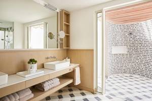 Badezimmer im LUX Grand Gaube Resort & Villas mit heller Beleuchtung, modernen Möbeln und einer Wand mit Text.