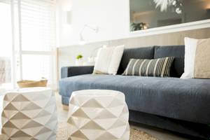Wohnbereich im LUX Grand Gaube Resort & Villas mit grauem Sofa, weißen Beistelltischen und einem gerahmten Bild an der Wand.