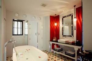 Badezimmer im Moracea by Khao Lak Resort mit Badewanne, Waschbecken und rotem Wanddesign.