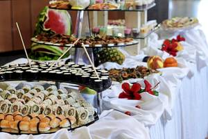 Ein Buffet-Tisch mit verschiedenen Sushi-Rollen und frischen Früchten.