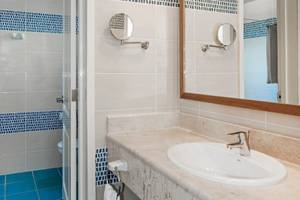 Badezimmer im Iberostar Tainos Hotel mit blauen Fliesen und Spiegeln.